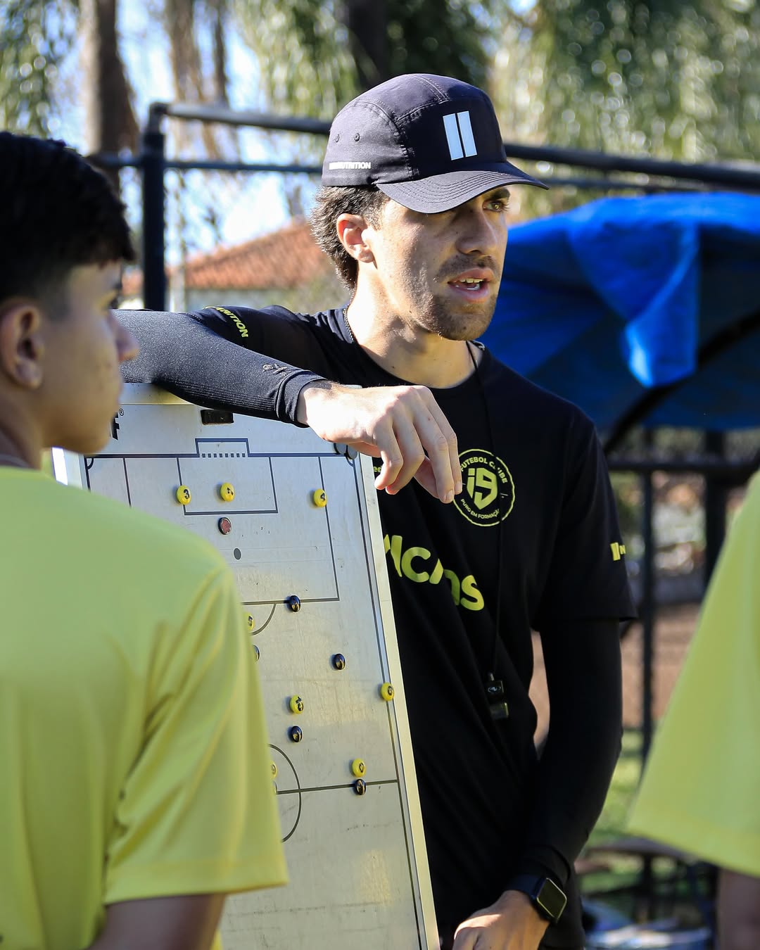 Treinador da i9 orientando atletas com uma prancheta tática